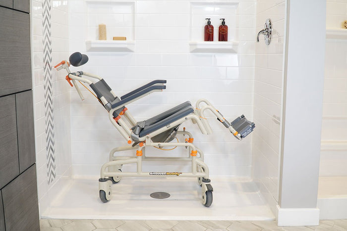 Advanced Showerbuddy chair positioned in a modern bathroom setting, showcasing its reclining feature and secure armrests for independent or assisted bathing.