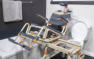 A Showerbuddy bath transfer system with a sliding seat mechanism for safely moving a person from a wheelchair to the bathtub.