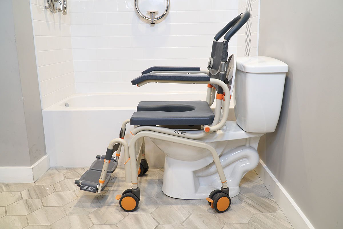 Close-up view of a commode chair, a part of the Showerbuddy bathroom mobility system, placed next to a toilet, highlighting its role in assisting individuals with special needs.