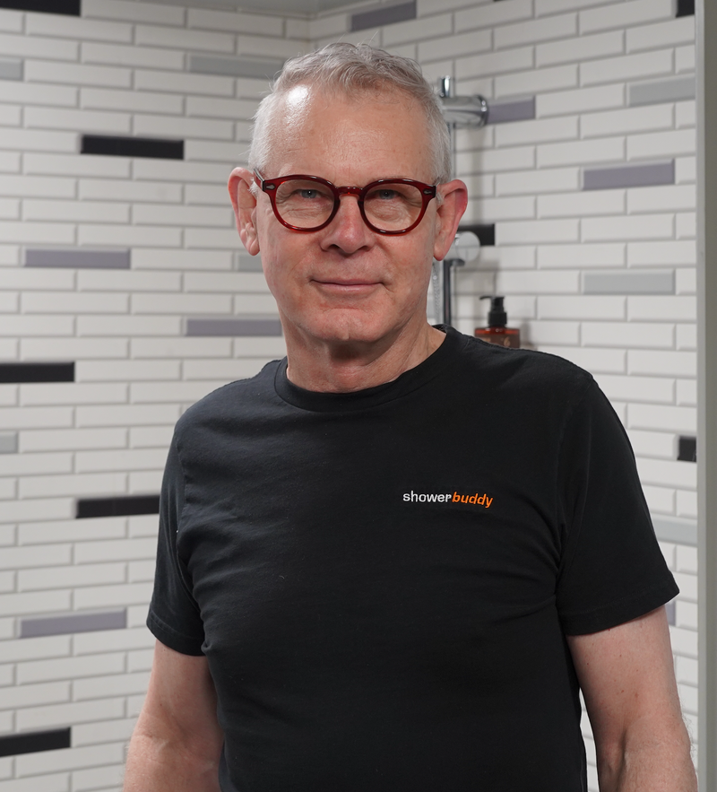 Smiling representative in a Showerbuddy branded shirt standing in a bathroom setting, representing the company's commitment to providing world-class support for their products.