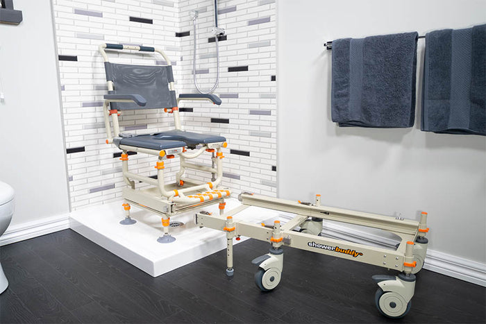 Image of a Showerbuddy bathroom transfer system installed in a modern bathroom, showcasing the mobility chair and transfer track against a backdrop of white tiles and dark flooring.
