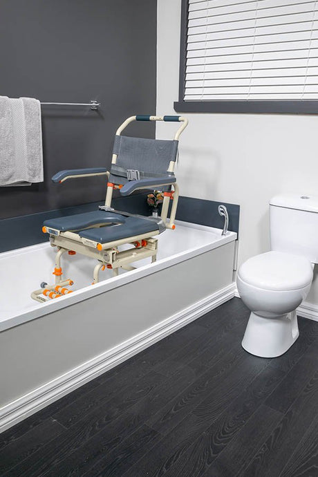 Showerbuddy tub transfer chair system installed on a bathtub in a contemporary bathroom with dark wood floors, white bathtub, and adjacent toilet, highlighting the ease of transfer and bathing accessibility.