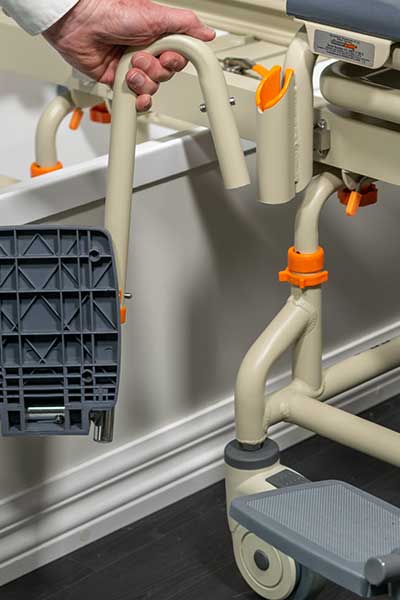 Image showing the adjustable framework of a Showerbuddy chair, with a hand operating the height adjustment mechanism.