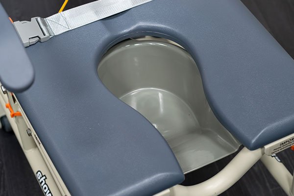 Close-up photo of a Showerbuddy commode chair's seat with description highlighting its multifunctional support for the entire bathroom process, providing a complete bathroom mobility solution.