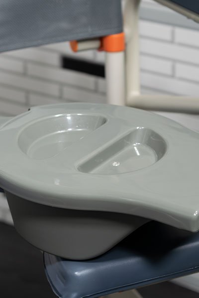 Detailed image of a removable pail from a Showerbuddy commode chair, emphasizing the feature of easy pail removal for convenience and hygiene.