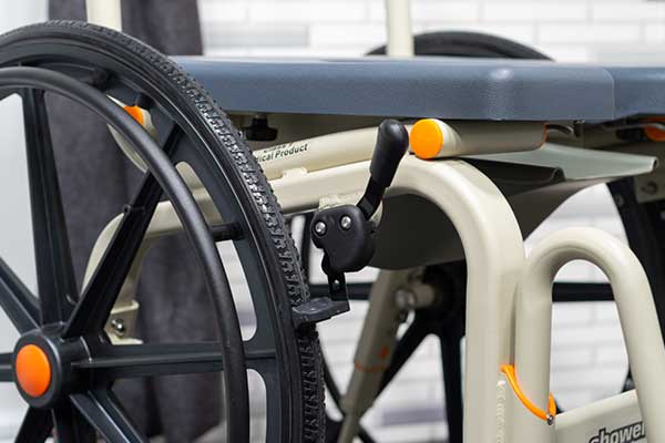 Close-up image of a Showerbuddy chair's wheel and brake system, featuring a wheelchair-style self-propel option for user independence.